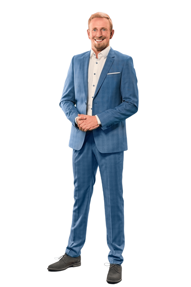 Mann in blauem Anzug mit weißem Hemd und blauen Schuhen, lächelt freundlich.